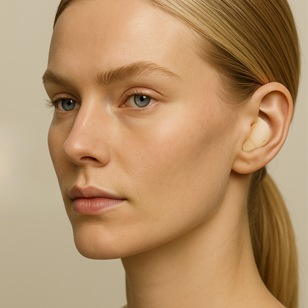 Close-up of a woman wearing a hearing aid on a beige background