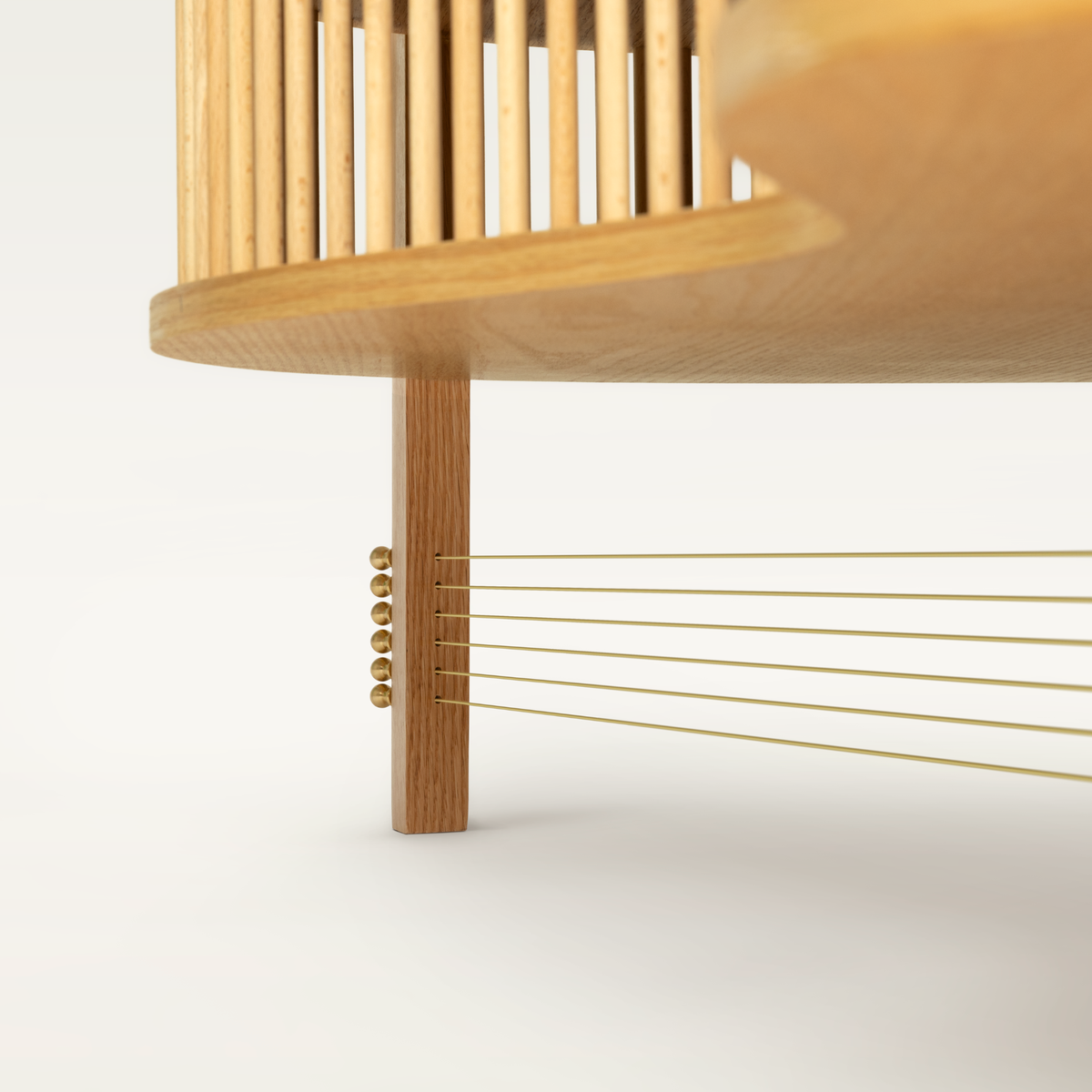Six brass strings tension and stabilize the three legs - transforming functional structure into a sculptural detail inspired by acoustic guitars.